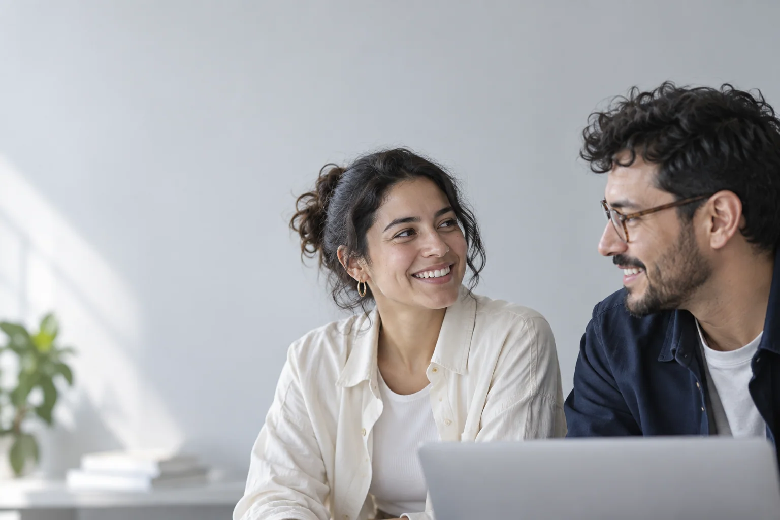 Dos personas conversan frente a un computador mientras trabajan en un proyecto